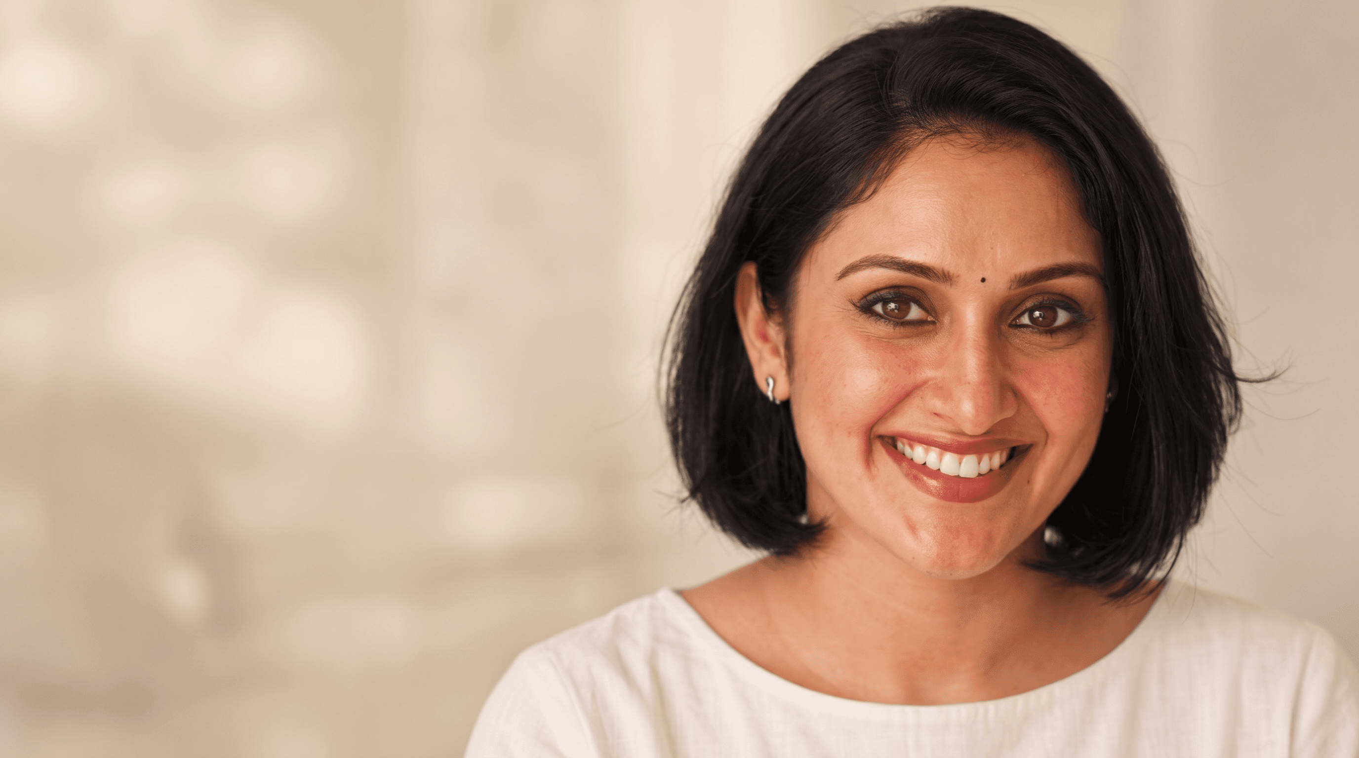 A woman in a white top with a warm, natural smile